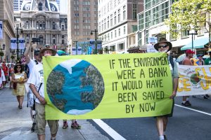 Protesters with sign: Iif the environment were a bank, it would have been saved by now"